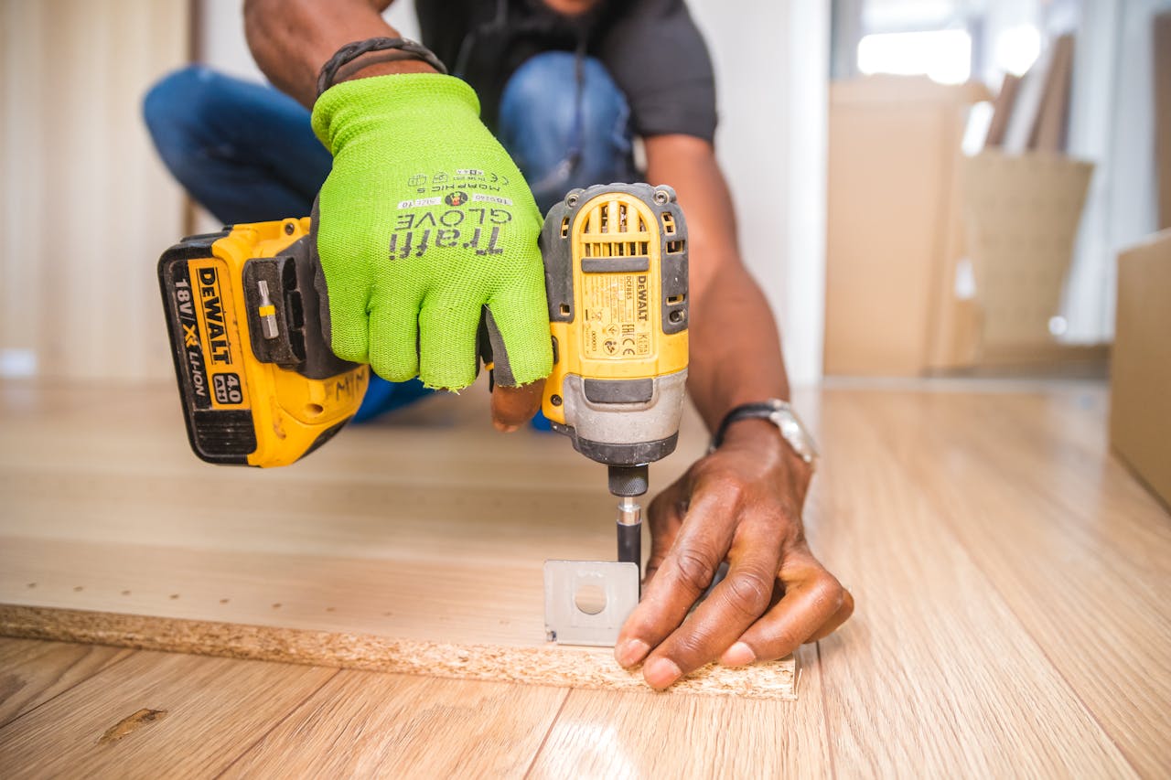 who-we-are Man using a power drill for home improvement on a wooden floor with precision.